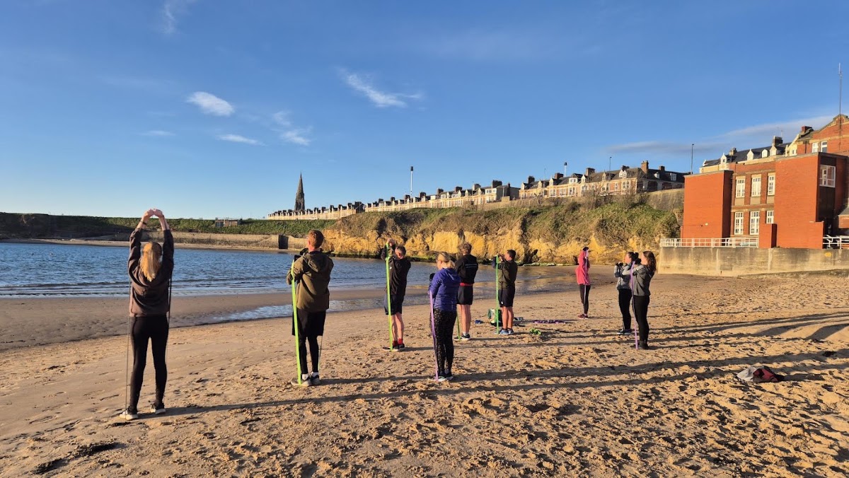 Bex leading a warm-up with the group on Cullercoats beach