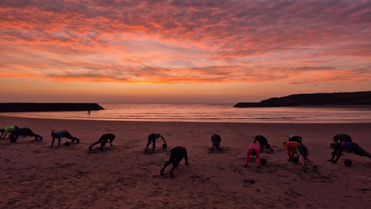 Beach bootcamp doing press-ups under a blazing sunrise on Cullercoats bay